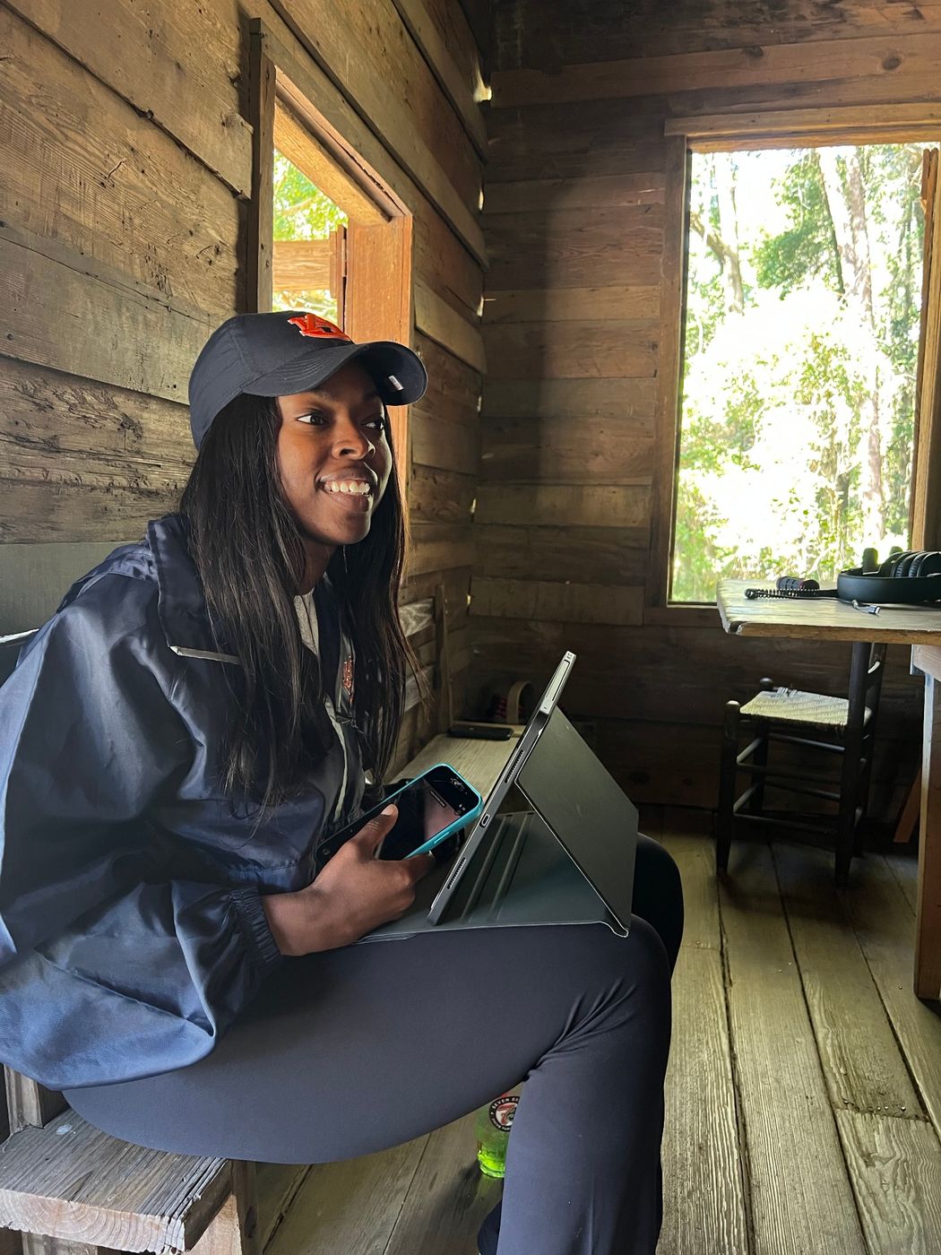 A cast member resting with a tablet beside a sunlit cabin window