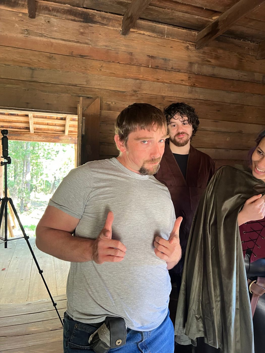 A crew member gesturing playfully beside cast in the cabin doorway