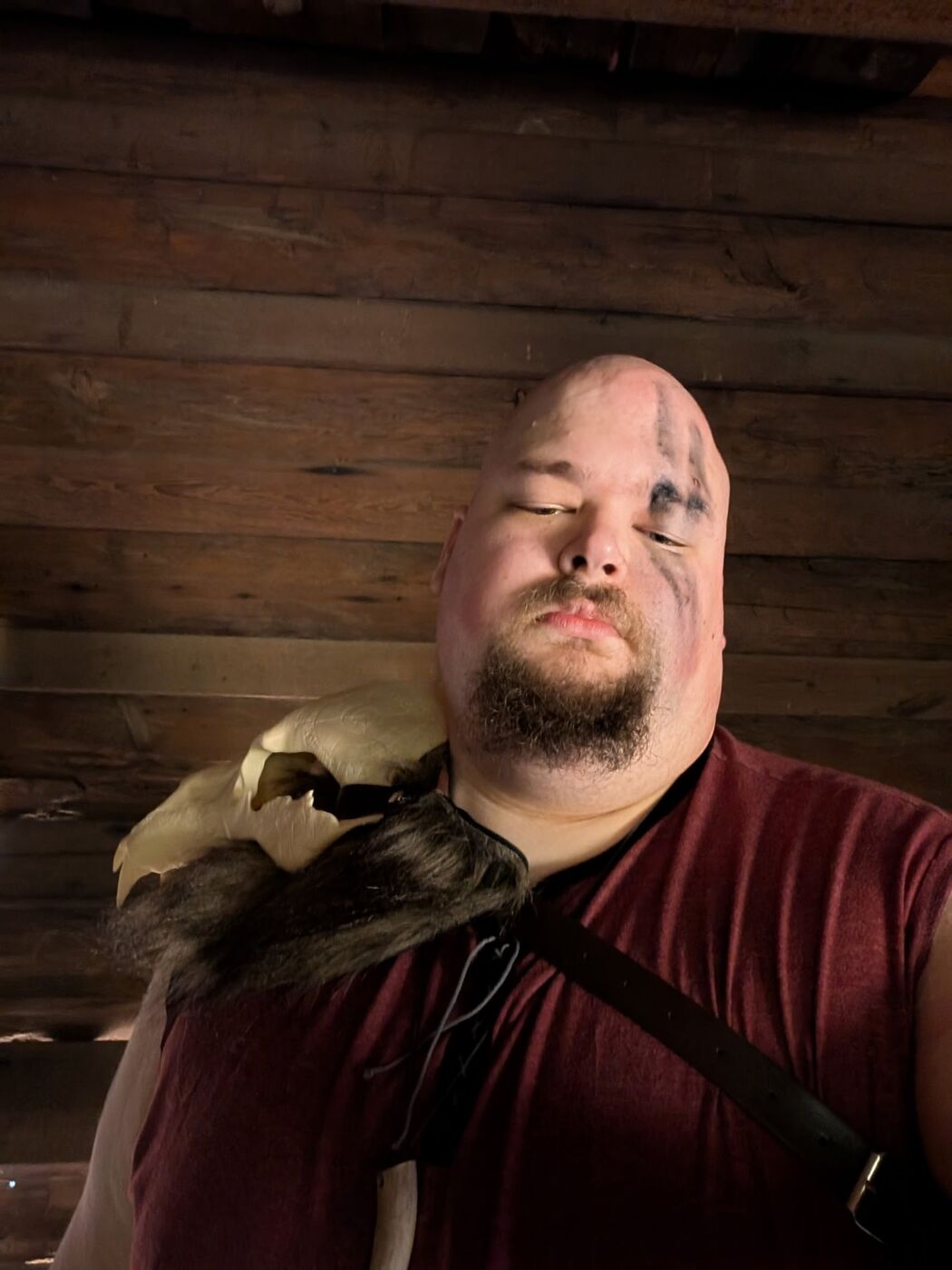 A costumed warrior with face paint and a fur shoulder piece, photographed low beneath the cabin ceiling