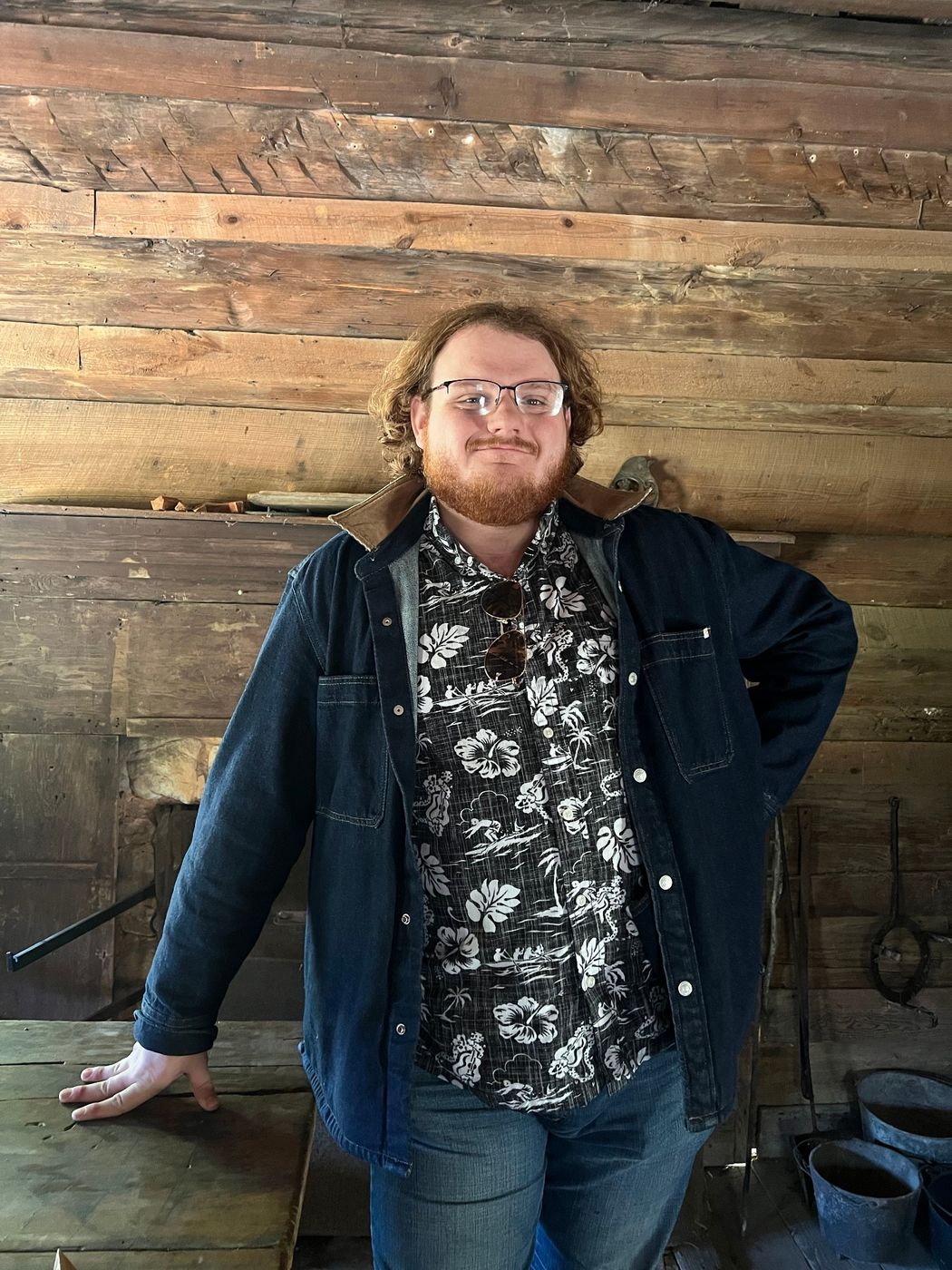 A crew member leaning on a table in front of a stone hearth
