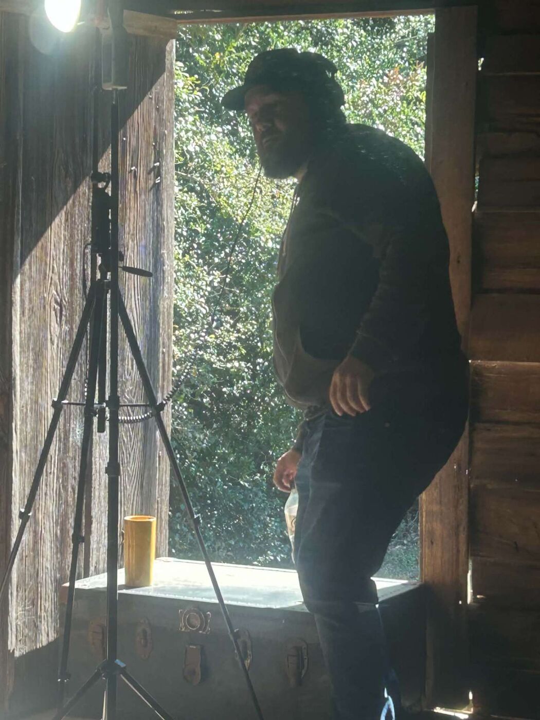 A crew member standing in the cabin doorway beside a production light on a stand